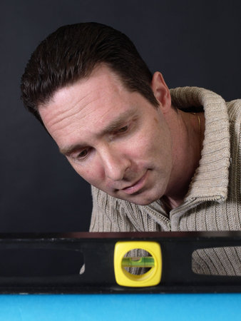 A man holding a level checks to make sure his project is straight.