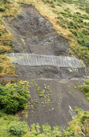Unstable land has a net to catch any more lose rock.の写真素材