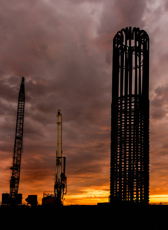 Crane and a drill standing tall at sunset.の写真素材