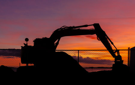 Excavator parkup for a the end of the day. with a woinderful warm sunset sky behind it.