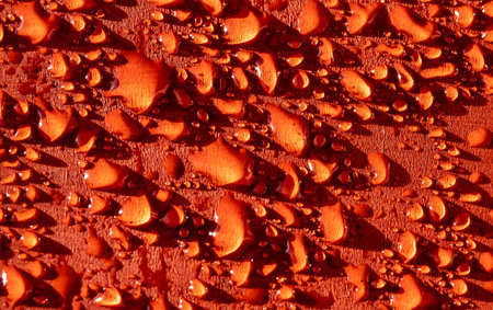 Water droplets on a red surface area.