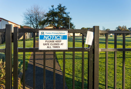 Foxton , Horowhenua, New Zealand, 08.21.2021. White face mask on a school gate sybolising that...
