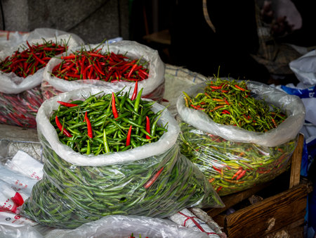 In a vibrant street market of Bangkok, Thailand, sizable sacks brim with spicy chili fruits in...