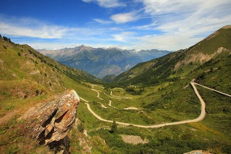View on unpaved road running through the valley in Alps, Italy.の写真素材