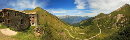 Panoramic view on ancient fortifacation and unpaved road tjrough the valley in Alps, Italy.のeditorial素材