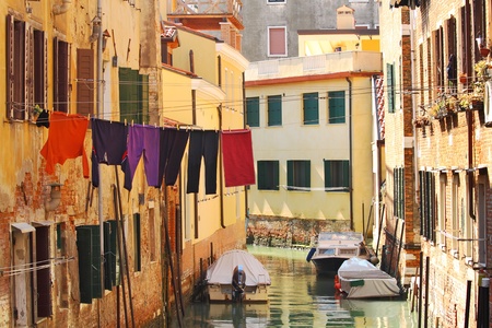 Small canal with boats among old brick houses with washed clothes in Venice, Italy.の写真素材