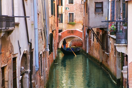 Gondola on small canal among old historic houses in Venice, Italy.の写真素材