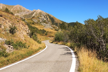 Narrow road running through the hills and peaks of Alps - mountains in northern Italy.の写真素材