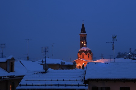 Night view on snowy roofs and illuminated church Madonna Moretta in Alba, northern Italy.の写真素材