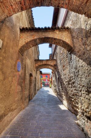 Vertical oriented image of arched pathway among ancient brick walls in Sirmione, Northern Italy の写真素材