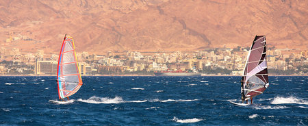 Two surfers on windsurfing boards gliding on surface at the Red Sea in Eilat, Israel 