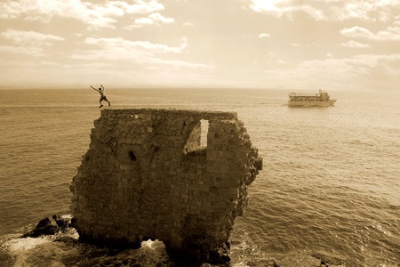 Unidentified person jumps from ancient wall remains in port of Acre on Mediterranean sea in Israe の写真素材