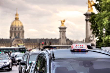 Parisian taxi illuminated sign on the car roof and Les Invalides on the background in Paris, France.の写真素材