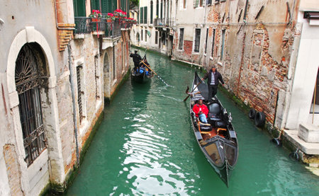VENICE - MAR 28: Gondola with tourists passing on narrow canal among old historic buildings in Venice, Italy on March 28, 2008.のeditorial素材