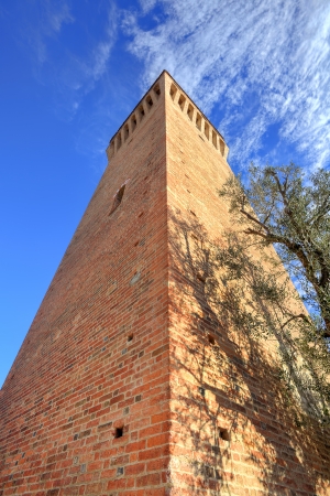 Vertical oriented image of medieval brick tower under blue sky at Santa Vittoria D'Alba in Piedmont, Northern Italy.の写真素材