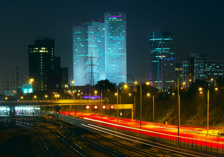Night view of Tel Aviv city downtown, illuminated Azrieli towers and light traces on Ayalon highway 