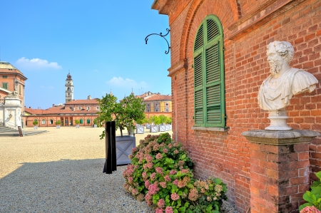 Bust on pedestal on the gravel pathway next to red brick house at the entrance to park and Royal Castle of Racconigi in Piedmont, Northern Italy の写真素材
