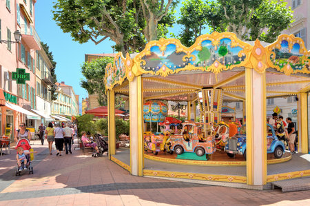 MENTON - JUN 13: Childrens carousel on the main pedestrian street in small resort town on the Cote d\'Azur (aka French Riviera) popular among tourists from all over the world in Menton, France on June 13, 2013.のeditorial素材