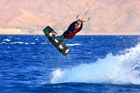 EILAT, ISRAEL - MARCH 31  Unidentified kite surfer jumps in the air leaving splashes during local...