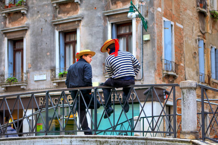 VENICE - NOVENBER 13  Two gondoliers in traditional dress sitting on bridge  Gondolier must be Venetian by birth, it is one of the oldest professions in the world controlled by a Guild in Venice, Italy on November 13, 2012 のeditorial素材