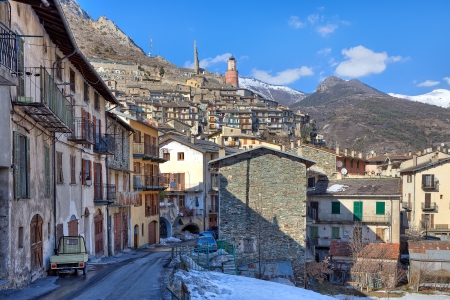 Narrow street among old stone houses and mountains on background in Tende - small alpine town on French - Italian border の写真素材