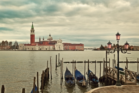 Gondolas tied on Grand Canal and San Giorgio Maggiore church on background under cloudy sky in Venice, Italy の写真素材