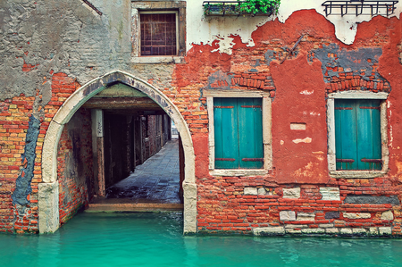 Narrow canal and facade of old red brick house in Venice, Italy の写真素材