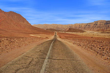 Paved road runs through Arava desert among red mountains in Timna national park, Israel の写真素材