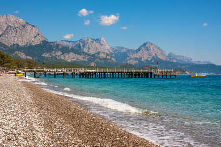 Pier on shingle beach and aquamarine water in popular touristic resort of Kemer on Mediterranean sea in Turkey の写真素材
