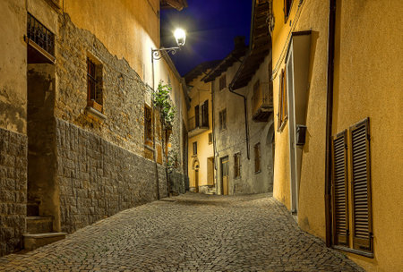 Narrow cobbled street among old houses at night in town of Barolo, Italy の写真素材