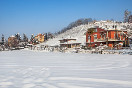 Houses and rural field covered with snow in Piedmont, Northern Italy.の写真素材