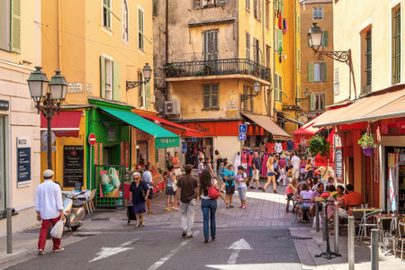 NICE FRANCE  AUGUST 23 2014: Tourists sitting in outdoor restaurants and walking in Old City of Nice  fifth most populous and secondlargest French city on Mediterranean coast and one of the most visited receiving 4 million tourists every year.のeditorial素材