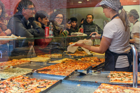 ALBA, ITALY - NOVEMBER 15, 2015: People inside typical pizzeria buying pizza - traditional italian dish invented in Naples, very popular in all over the world.のeditorial素材