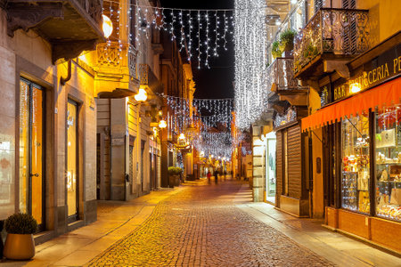 ALBA, ITALY - DECEMBER 06, 2012: Pedestrian street and shops in old town illuminated and decorated for Christmas and New Year holidays. This area is very popular with locals and tourists visiting Alba for holidays.のeditorial素材