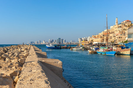 View from breakwater on small port with boats, old Jaffa and Tel Aviv on background under blue sky in Israel.の写真素材
