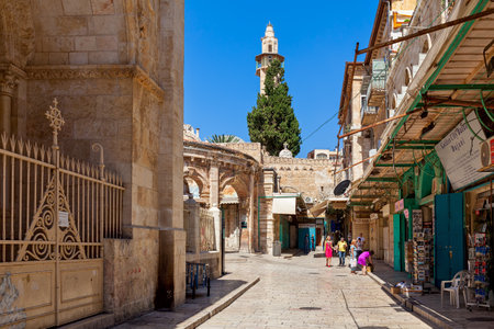 JERUSALEM, ISRAEL - JULY 04, 2016: Narrow street with souvenir shops as minaret on background in Muristan  - christian quarter, popular tourist destination, located in Old City of Jerusalem, Israel.のeditorial素材
