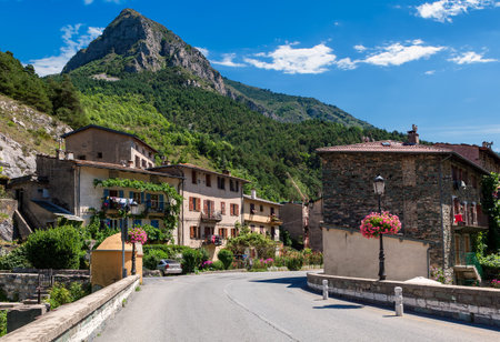 Road, rural houses and mountain on background under blue sky in small town of Tende, France.の写真素材