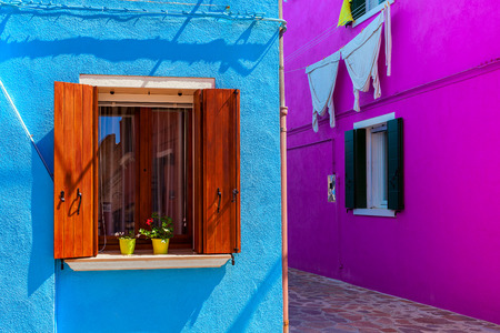 Walls painted in vivid colors with windows and wooden shutters in Burano, Italy.の写真素材