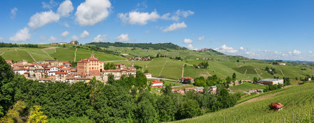 Small medieval town of Barolo and green hills and vineyard under blue sky in Piedmont, Northern...