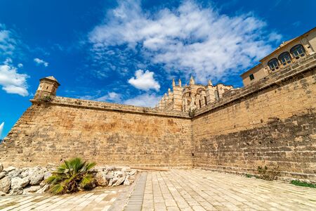 Famous Cathedral of Santa Maria and surrounding medieval wall under blues sky in Palma de Mallorca, Spain.の写真素材