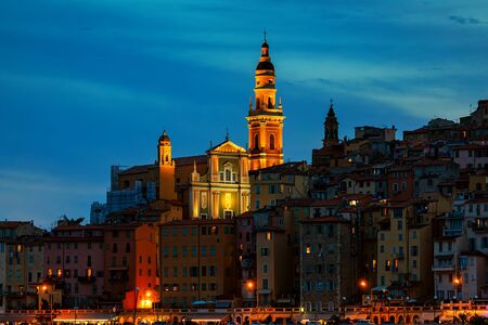 Evening view on houses and illuminated basilica of Saint Michel Archange in old town of Menton, France.の写真素材