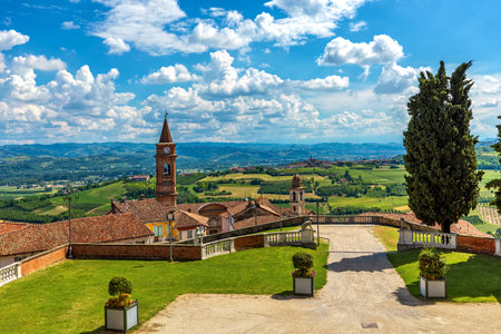 Old town of Govone overlooking green hills under beautiful blue sky with white clouds in Piedmont, Northern Italy.の写真素材