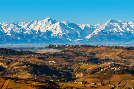 View from above of autumnal hills and snowy mountains on background under blue sky in Piedmont, Northern Italy.の写真素材