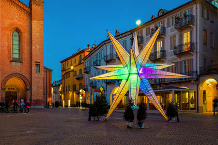 Illuminated colorful Christmas star on old town square in Alba, Piedmont, Northern Italy.の写真素材