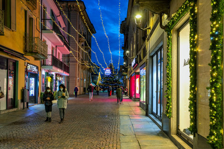 ALBA, ITALY - DECEMBER 15, 2020: People walking on cobblestone street in the old town illuminated and decorated for Christmas holidays in Alba - capital of Langhe, famous tourist destination in Piedmont, Northern Italy.のeditorial素材