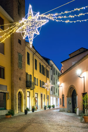 Evening town street in historic center of Alba, Italy illuminated and decorated for Christmas holidays.の写真素材