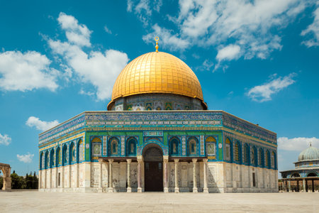 The famous Dome of the Rock mosque standing out against a vibrant blue sky dotted with fluffy white clouds in the old city of Jerusalem, Israel.の写真素材
