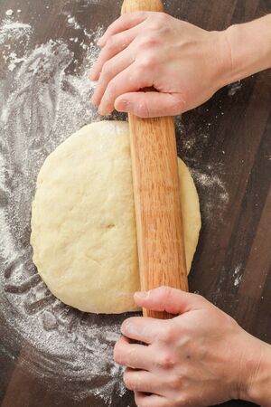 Rolling dough with rolling pin on the tableの写真素材