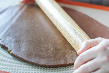 Rolling dough with rolling pin on the tableの写真素材