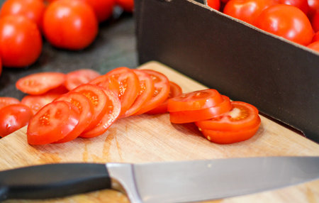 Sliced tomatoes on the wooden board with the kinfe